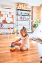 Young beautiful blonde girl kid enjoying play school with toys at kindergarten, smiling happy playing with inteligence toys at