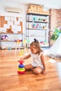 Young beautiful blonde girl kid enjoying play school with toys at kindergarten, smiling happy playing with inteligence toys at