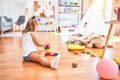 Young beautiful blonde girl kid enjoying play school with toys at kindergarten, smiling happy playing with inteligence toys at