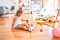 Young beautiful blonde girl kid enjoying play school with toys at kindergarten, smiling happy playing with inteligence toys at