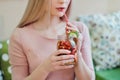 Young beautiful blonde girl in a pink dress sits at a cafe table, drinks lemonade from a glass jar. Royalty Free Stock Photo