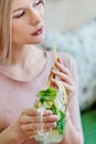 Young beautiful blonde girl in a pink dress sits at a cafe table, drinks lemonade from a glass jar. Royalty Free Stock Photo