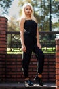 Young beautiful blonde girl posing on the background of the urban landscape. lady in a black dress. Royalty Free Stock Photo