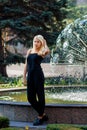 Young beautiful blonde girl posing on the background of the urban landscape. lady in a black dress . Royalty Free Stock Photo