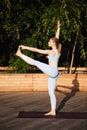 Young beautiful blonde girl practicing yoga outside at sunrise. Royalty Free Stock Photo