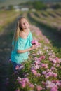Young beautiful blonde girl on a rose plantation .