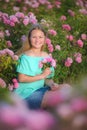 Young beautiful blonde girl on a rose plantation .