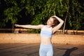 Young beautiful blonde girl smiling, practicing yoga outside at sunrise.