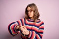 Young beautiful blonde girl wearing glasses and casual sweater over pink isolated background Checking the time on wrist watch, Royalty Free Stock Photo