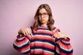 Young beautiful blonde girl wearing glasses and casual sweater over pink isolated background Pointing down looking sad and upset, Royalty Free Stock Photo