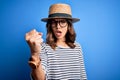 Young beautiful blonde girl wearing glasses and hat over blue isolated background annoyed and frustrated shouting with anger, Royalty Free Stock Photo