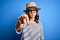 Young beautiful blonde girl wearing glasses and hat over blue isolated background pointing with finger to the camera and to you, Royalty Free Stock Photo