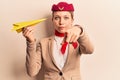 Young beautiful blonde girl wearing stewardess uniform holding paper plane pointing with finger to the camera and to you, Royalty Free Stock Photo
