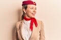 Young beautiful blonde girl wearing stewardess uniform looking away to side with smile on face, natural expression