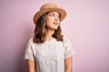 Young beautiful blonde girl wearing summer hat over pink isolated background looking away to side with smile on face, natural Royalty Free Stock Photo