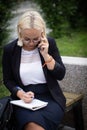 Young beautiful blonde in glasses talking on a smartphone and laughing. Business woman on the street with a phone in her Royalty Free Stock Photo