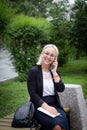 Young beautiful blonde in glasses talking on a smartphone and laughing. Business woman on the street with a phone in her Royalty Free Stock Photo