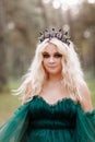 Young beautiful blonde hair woman queen. Princess walks. autumn green forest mystic. Vintage medieval shiny crown. Long evening Royalty Free Stock Photo