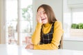 Young beautiful blonde kid girl wearing casual yellow sweater at home covering one eye with hand, confident smile on face and Royalty Free Stock Photo