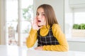 Young beautiful blonde kid girl wearing casual yellow sweater at home hand on mouth telling secret rumor, whispering malicious Royalty Free Stock Photo