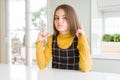 Young beautiful blonde kid girl wearing casual yellow sweater at home Pointing up looking sad and upset, indicating direction with Royalty Free Stock Photo