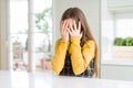 Young beautiful blonde kid girl wearing casual yellow sweater at home with sad expression covering face with hands while crying Royalty Free Stock Photo
