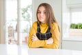 Young beautiful blonde kid girl wearing casual yellow sweater at home shaking and freezing for winter cold with sad and shock Royalty Free Stock Photo