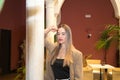 Young and beautiful blonde Latin woman is leaning against a marble column in the inner courtyard of a hotel. The woman is sad and