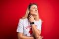 Young beautiful blonde lifeguard woman wearing t-shirt with red cross and whistle Touching painful neck, sore throat for flu, clod