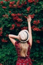 Young beautiful blonde long haired woman in red dress and straw hat standing backwards with raised hands over green Royalty Free Stock Photo