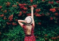 Young beautiful blonde long haired woman in red dress and straw hat standing backwards with raised hands Royalty Free Stock Photo