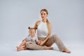 A young beautiful blonde mother and a girl in a fashionable white T-shirt and beige knitted trousers are sitting on the floor Royalty Free Stock Photo