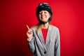 Young beautiful blonde motorcyclist woman wearing motorcycle helmet over red background with a big smile on face, pointing with Royalty Free Stock Photo