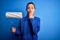 Young beautiful blonde painter woman with blue eyes painting wearing uniform using roller cover mouth with hand shocked with shame Royalty Free Stock Photo