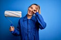 Young beautiful blonde painter woman with blue eyes painting wearing uniform using roller with happy face smiling doing ok sign Royalty Free Stock Photo