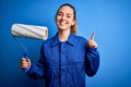 Young beautiful blonde painter woman with blue eyes painting wearing uniform using roller surprised with an idea or question Royalty Free Stock Photo