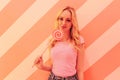 Young beautiful blonde in a pink blouse on the soft pink background with multi-colored bright pink lollipop Royalty Free Stock Photo