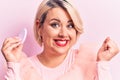 Young beautiful blonde plus size woman applying makeup using sponge over pink background screaming proud, celebrating victory and Royalty Free Stock Photo