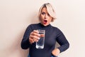 Young beautiful blonde plus size woman drinking glass of water over isolated white background scared and amazed with open mouth Royalty Free Stock Photo