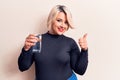 Young beautiful blonde plus size woman drinking glass of water over isolated white background smiling happy and positive, thumb up Royalty Free Stock Photo