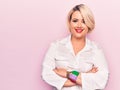 Young beautiful blonde plus size woman wearing elegant shirt over isolated pink background happy face smiling with crossed arms Royalty Free Stock Photo