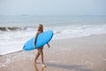 Young and beautiful blonde surfer woman in pink bikini and blue surfboard. The girl enjoys her holidays on the beach to practice Royalty Free Stock Photo