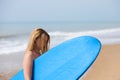 Young and beautiful blonde surfer woman in pink bikini and blue surfboard. The girl enjoys her holidays on the beach to practice Royalty Free Stock Photo