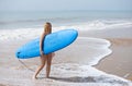 Young and beautiful blonde surfer woman in pink bikini and blue surfboard. The girl enjoys her holidays on the beach to practice Royalty Free Stock Photo