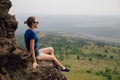 Young beautiful blonde tourist girl sits on a rocky ledge of a rock Royalty Free Stock Photo