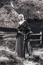 Young beautiful blonde woman with a bicycle in the yard in rural areas. black-white