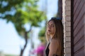 Young, beautiful blonde woman in black skirt and black top is leaning against brick wall and looking at camera with angry and Royalty Free Stock Photo