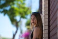 Young, beautiful blonde woman in black skirt and black top is leaning against brick wall and looking at camera with angry and Royalty Free Stock Photo