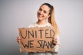 Young beautiful blonde woman with blue eyes asking for united stand holding banner with a happy face standing and smiling with a