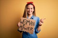 Young beautiful blonde woman with blue eyes asking for women rights holding banner very happy pointing with hand and finger to the